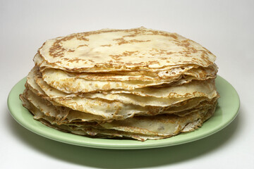 stack of blintzes, greased with butter. traditional product, on green plate. isolated on white...