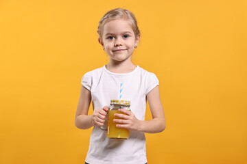 Girl with mason jar of juice on orange background. Refreshing drink