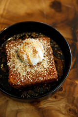 Fresh bread butter toast with Vanilla flavor ice cream on black ceramic plate on wooden table.