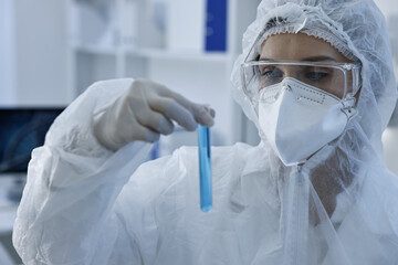 Scientist holding test tube with blue sample in laboratory