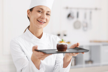 Happy confectioner with delicious coconut shaped dessert in kitchen
