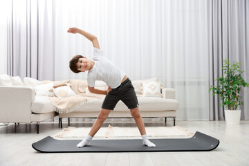Boy doing exercise on fitness mat at home. Sport activity
