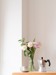 Coffee cup, moka pot and flowers creating cozy atmosphere on wooden table