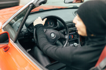 Woman drives car red convertible with top down, enjoying open air and sense of freedom. Motion, confidence, thrill of driving in stylish, sporty vehicle. Energy, independence, and modern lifestyle.