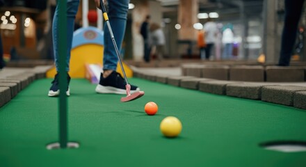 Person playing indoor mini-golf, focus on putting