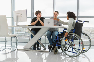 Teamwork brainstorm. Diverse multiracial colleagues woman in chair for people with disability working together. Group of people sitting in creative office discussing business. Young professional team