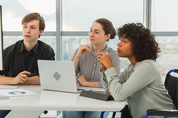 Obraz premium Teamwork brainstorm. Diverse multiracial colleagues woman in chair for people with disability working together. Group of people sitting in creative office discussing business. Young professional team