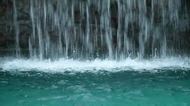 A waterfall flows fast into the pool