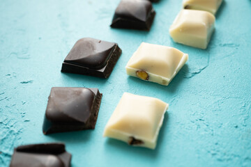 white milk chocolate, dark chocolate and dates on blue background in close-up