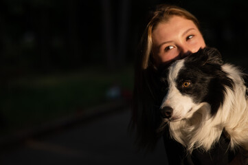 Young Caucasian woman hugging her border collie dog while walking in the park. 