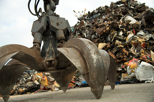 Large tracked excavator working a steel pile at a metal recycle yard. Industrial scrap metal recycling - selective focus, copy space - Powered by Adobe