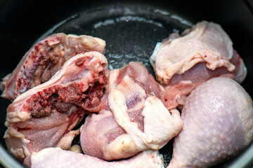 Fresh chicken drumsticks sprinkled with salt, resting in a cooking pot, ready for seasoning and preparation. Ideal for culinary and food photography