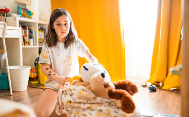 Child cleans up her toys in the room.	