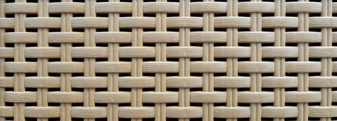 Close-up of woven plastic surface of laundry basket. Close-up of synthetic plastic pattern. Close-up of woven surfaces of plastic household baskets. Texture. Plastic rattan with symmetrical pattern