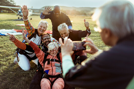 Group of senior people taking a photo after skydiving on a field
