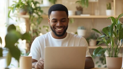 Smiling man working on his laptop surrounded by many vibrant, green plants