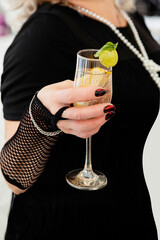 A man holds in his hand a colored cocktail with fruits in a glass glass.