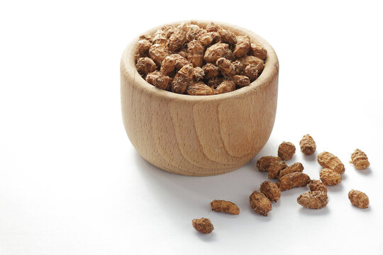 Tiger nut or nutsedge dry nuts in a wooden bowl isolated on white background, closeup, healthy food and dairy and gluten free eating concept