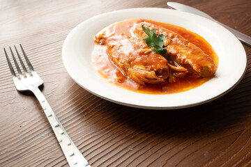 Bluefish with tomato sauce and olive oil served on a white plate in Mediterranean style