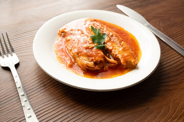 Bluefish with tomato sauce and olive oil served on a white plate in Mediterranean style