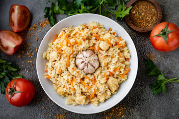Pilaf with chicken in a white plate on a gray background. Home cooking. Rice with chicken for lunch. View from above. Close-up