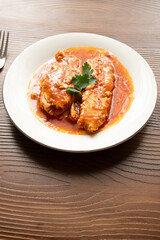 Bluefish with tomato sauce and olive oil served on a white plate in Mediterranean style