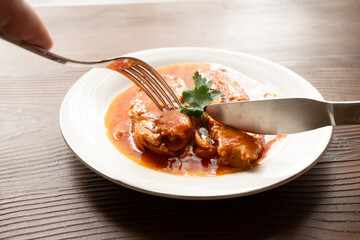 Bluefish with tomato sauce and olive oil served on a white plate in Mediterranean style