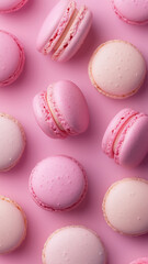 Obraz premium Neat rows of pink and cream macarons displayed on a smooth pink background—an elegant dessert wallpaper for phones.
