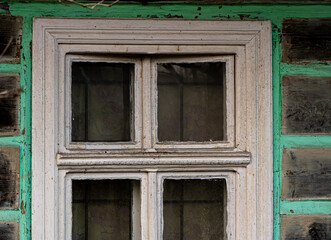 Old four-pane wooden window in a weathered timber house. The faded paint and aged wood reflect rural architecture, tradition, and the passage of time in a rustic setting