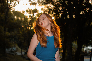 woman with long red hair in the wind wearing blue clothes with nature in the background