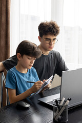 Two brothers focused on a laptop screen, deep in thought and learning. Online learning. Distance...