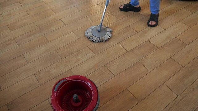 Professional cleaning professional wiping tiled surface using modern spinning mop and bucket, demonstrating thorough home maintenance and hygienic cleaning technique