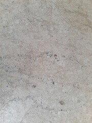 A textured beige marble surface with natural veins and speckles, featuring subtle brown and black accents. The stone's organic patterns create a natural and rustic aesthetic.	