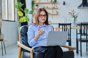 Middle aged woman working remotely, video conference, using laptop