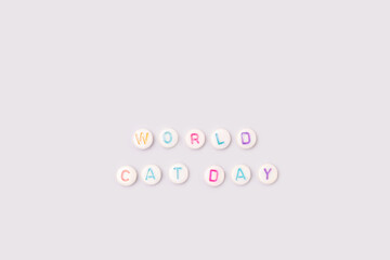 World Cat Day. Quote made of white round beads with multicolored letters on a blue background.