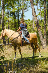 Side view, medium distance of, single female rider, looking back for two other riders, in tropical trees