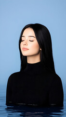 Serene woman with long black hair, partially submerged in water against a blue backdrop, eyes closed