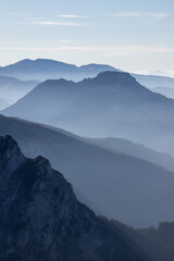 A breathtaking view along the trail to Giewont peak in the Polish Tatra Mountains. Layers of misty ridges stretch into the horizon, bathed in soft morning light.