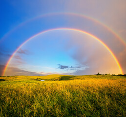 Naklejka premium Beautiful landscape of rainbow over the green grass fields