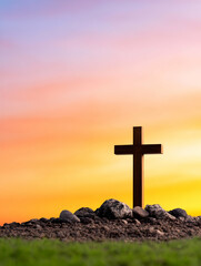 Silhouette of a wooden cross at sunset on a small rocky hill