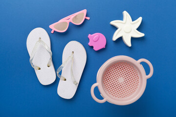 Children's flip flops and beach toys on color background,,top view
