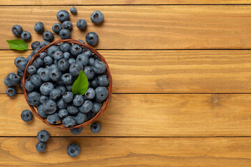 Bowl with fresh bright blueberries on wooden background,top view