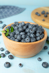 Bowl with fresh bright blueberries on wooden table
