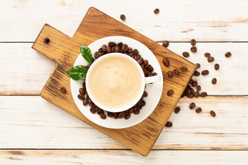 Cup of coffee with coffee beans and leaves on wooden background,top view