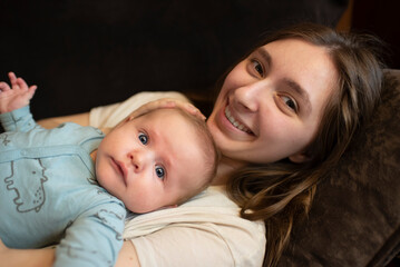 Teenage girl lying with her baby brother on the couch or Baby child lying on young mother.