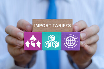 Business person or politician holding blocks with icons sees inscription: IMPORT TARIFFS. Import Tariffs Increase USA Trade concept. American Tariffs Growth Business Barrier International Commerce.
