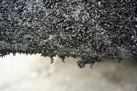 Close-up of rough asphalt texture edge
Detailed macro image of the edge of asphalt showing gritty, coarse texture with loose particles and uneven surface structure.

