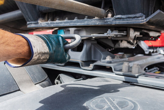 Man's hand pulling the lever to uncouple the truck from the semi-trailer, commonly known as the fifth wheel.