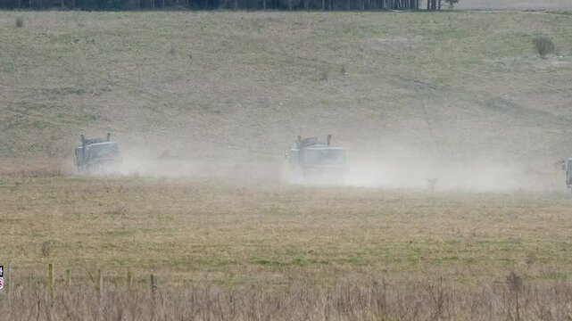 convoy of British army MAN EPLS 8x8 eight wheeled logistic trucks carrying supplies across countryside