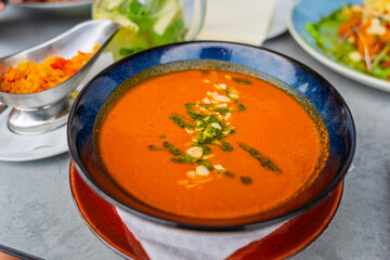 Fresh tomato soup with cheese and pesto sauce and pine nuts, served in blue bowl. Traditional Italian tomato soup.